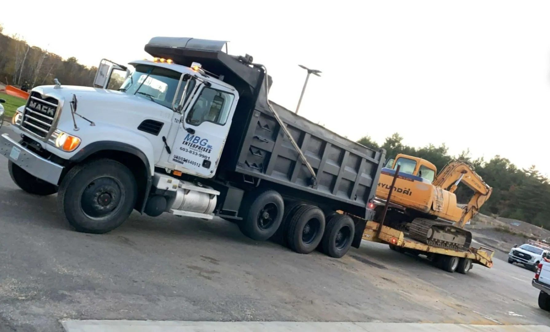 An MBG Mack tri-axle hauling an excavator on a lowbed trailer