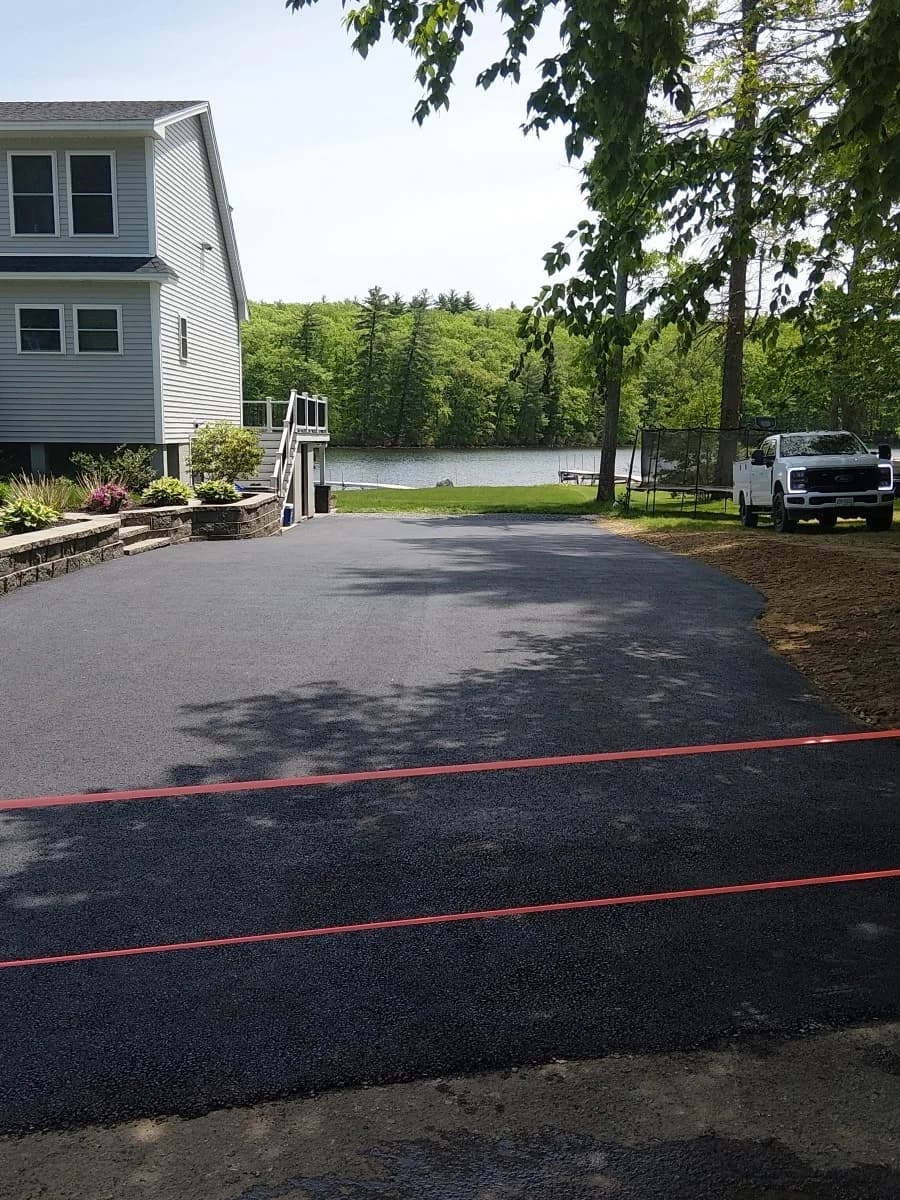A finished lakefront driveway with the water and treeline beyond