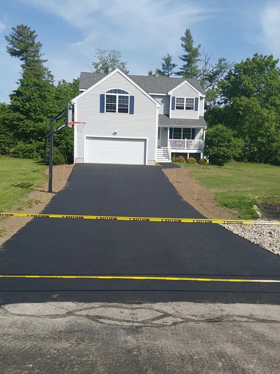 A newly paved residential driveway running the full frontage of a colonial home
