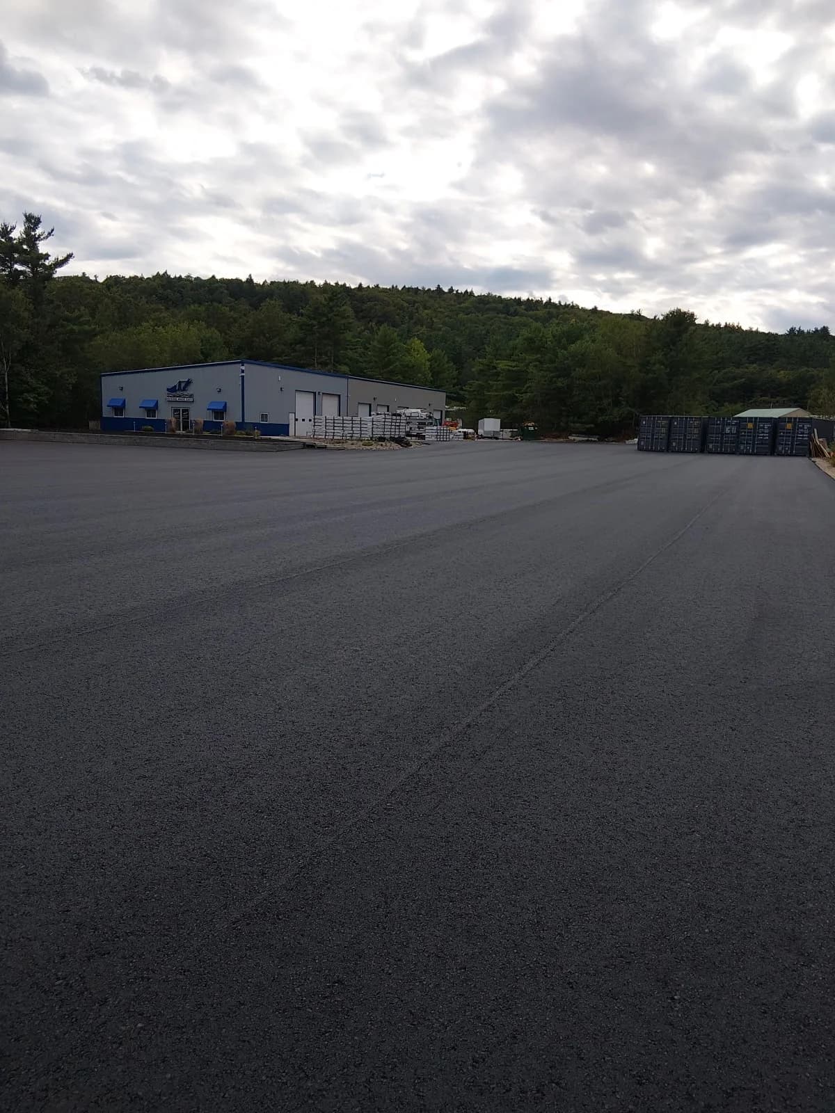 A freshly paved commercial parking lot in front of a warehouse building