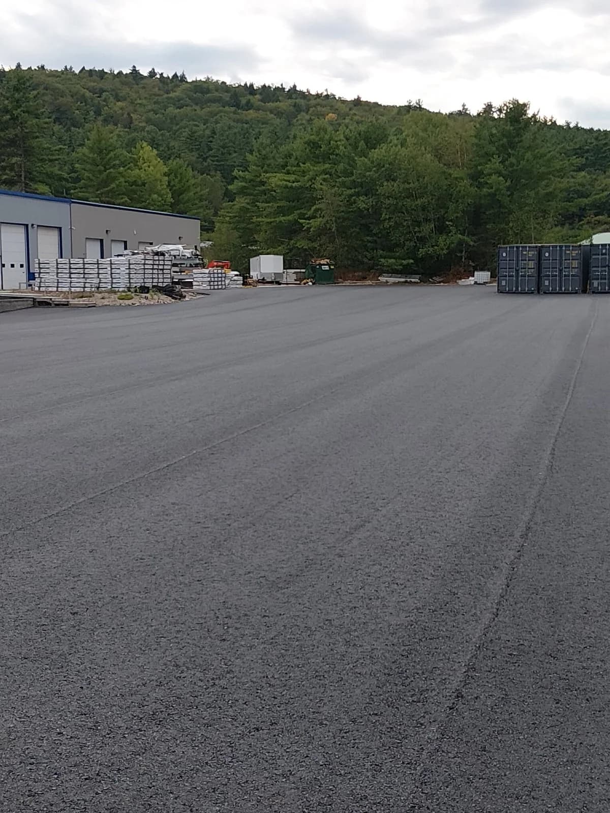 A wide view of a newly surfaced commercial lot backed by wooded hills